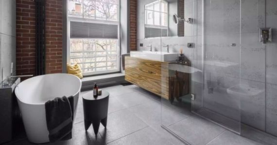 A master bathroom with a wooden finished vanity, a relaxing bathtub and a separate space for shower with a garden view