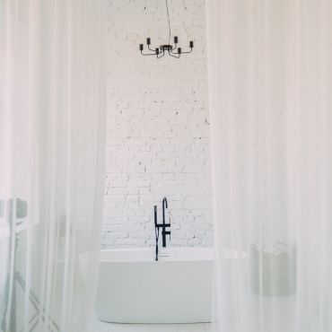 White can never go out of fashion. White tub placed in a white textured bathroom.