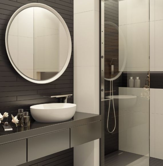 A bathroom with dark brown wooden finished vanity cabinet with a round mirror