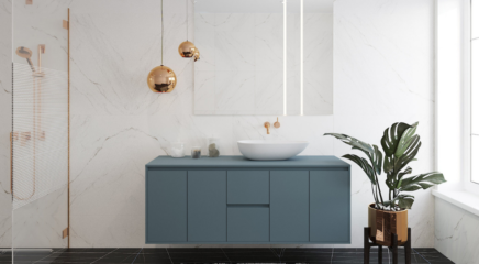 A white marble finish bathroom fitted with white ceramic sink, off blue color vanity cabinets. It has a copper finish tap and shower and lights which is hanging from the ceiling