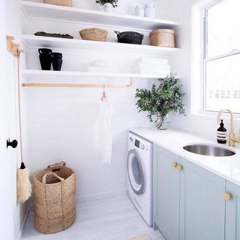 A white themed laundry room fitted with a front load washing machine and large laundry baskets, storage shelves and a garment rack