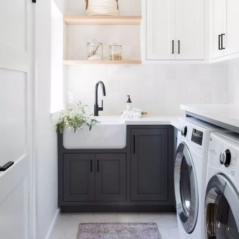 A white themed laundry room fitted with two white front load washing machines. Also, witted with a grey coloured sink tap and cupboard at the bottom and white colored cupboards at the top. 